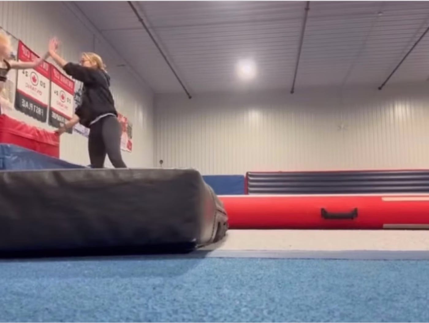 A CheerCore Jags coach spotting an athlete on a tumble track
