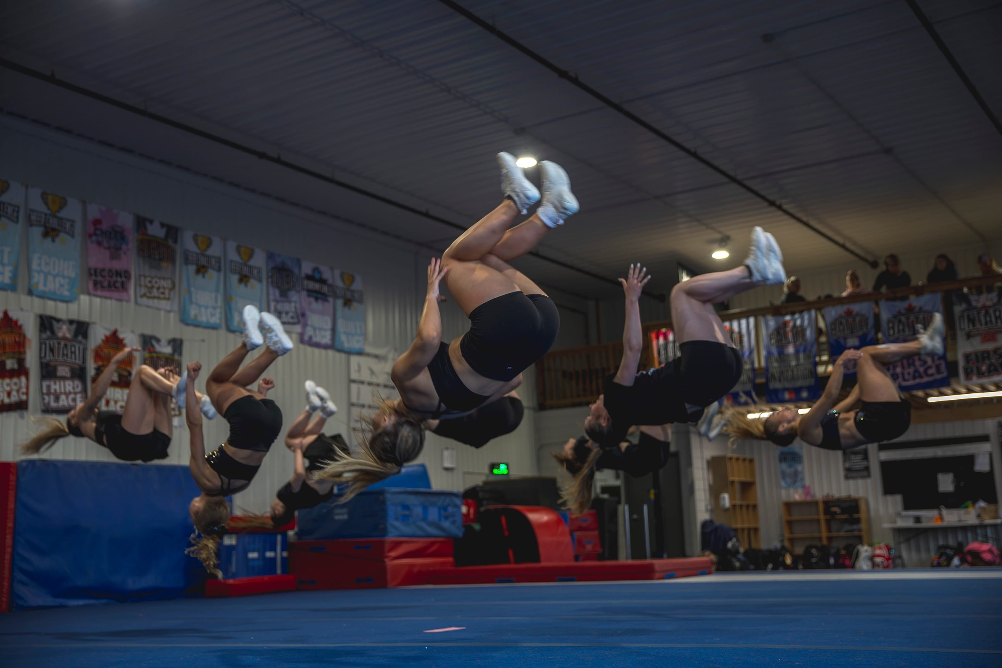 CheerCore Jags athletes performing synchronized backflips in the gym