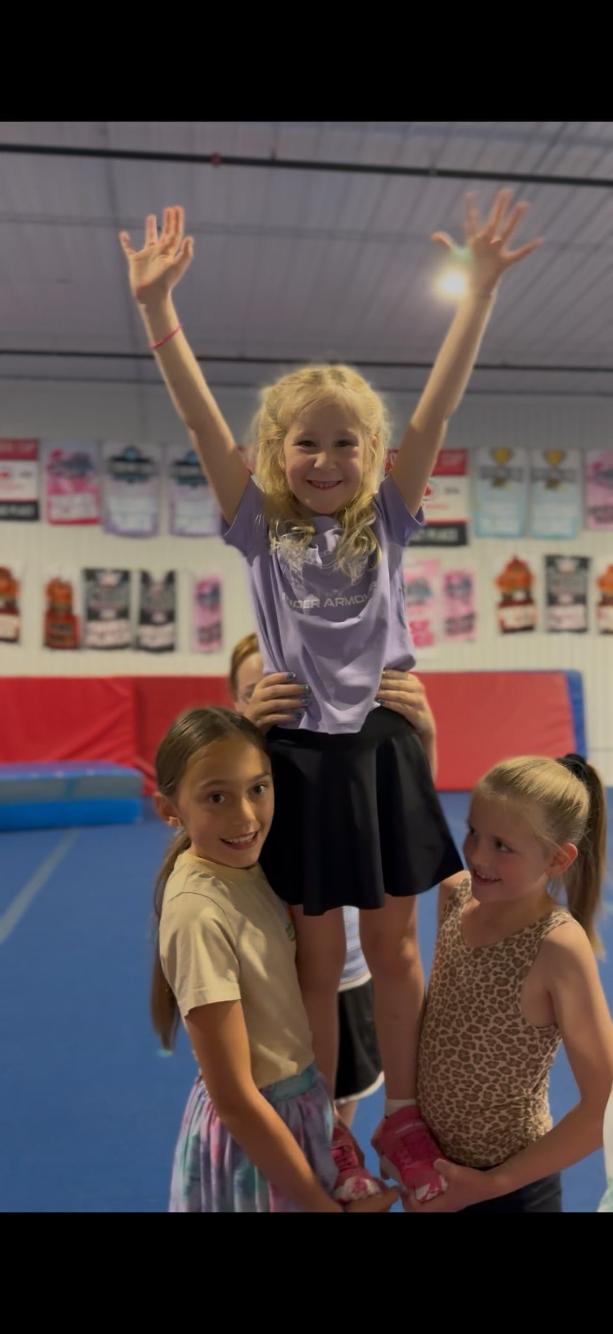 A young CheerCore Jags athlete held in a stunt by two teammates in the gym