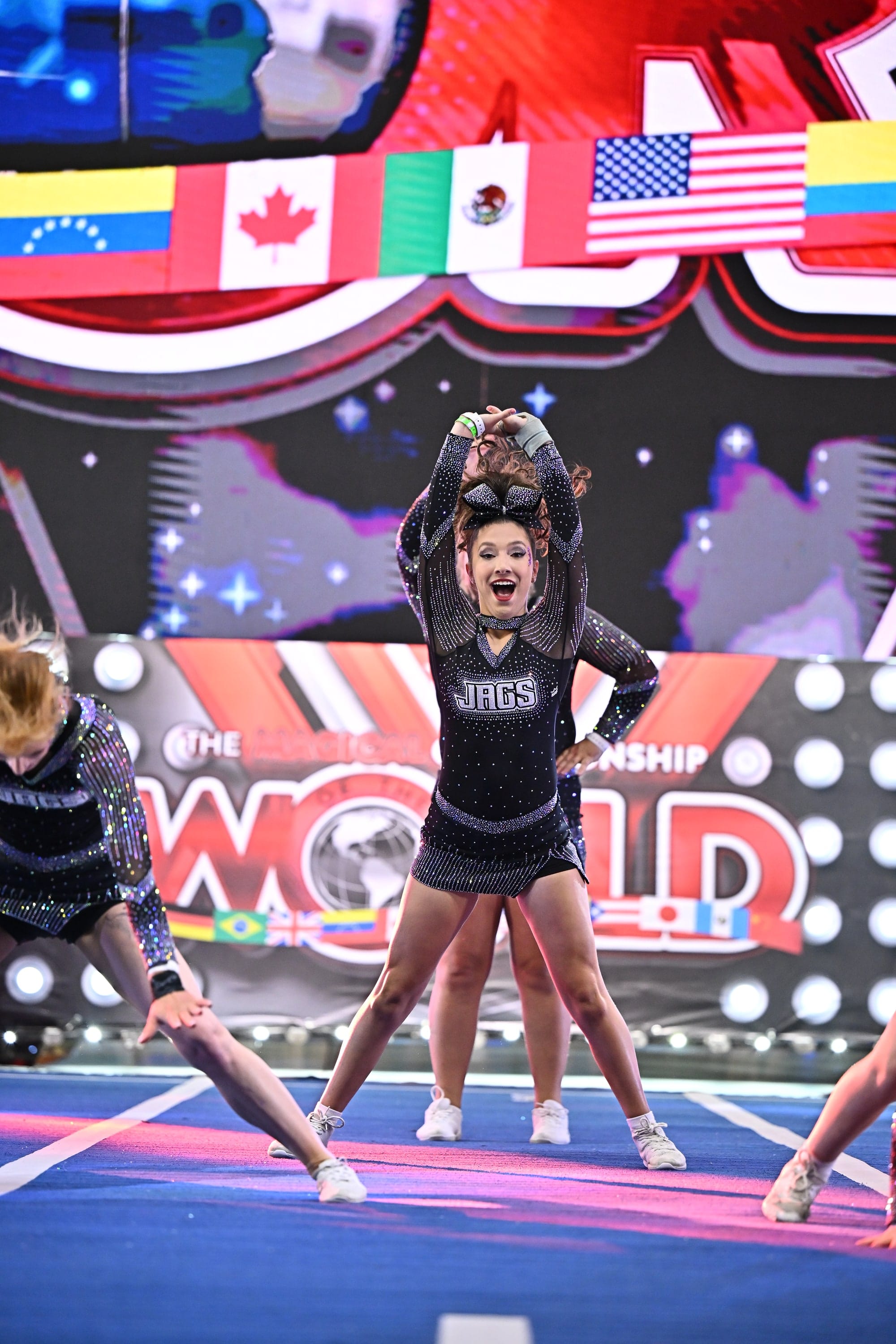 An Elite Cheer athlete hitting a jump on stage at the Cheerleading Worlds