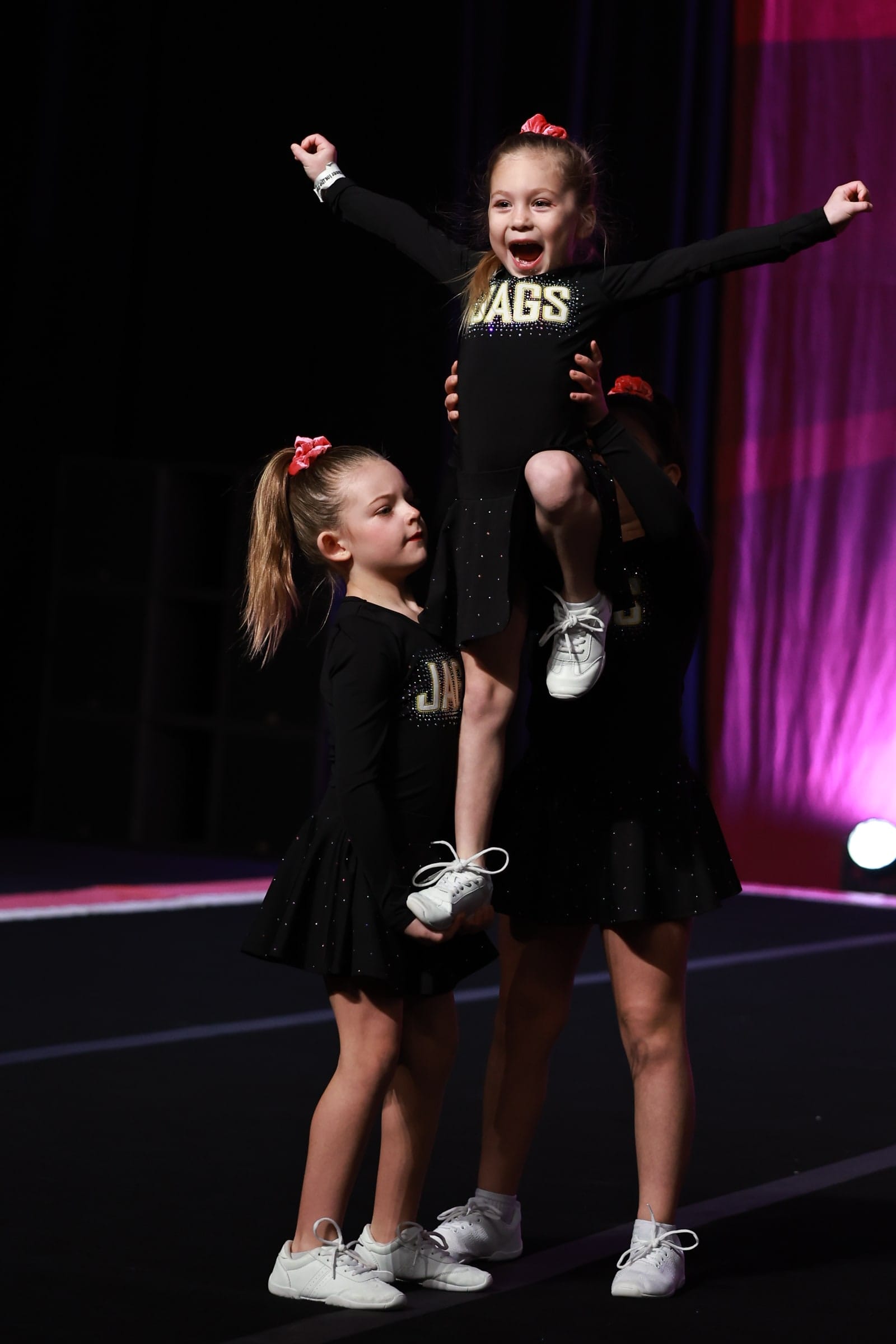 A Novice Cheer flyer held in a stunt by her teammates