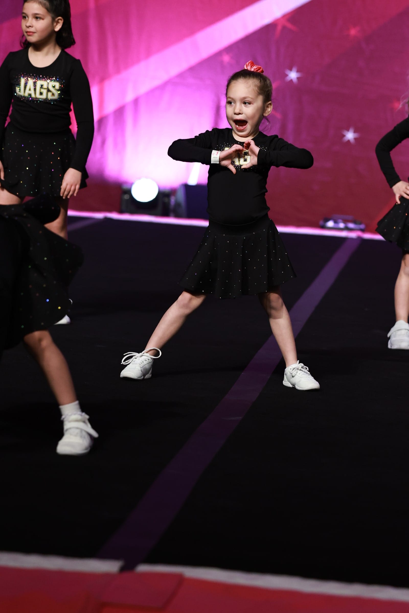 A Novice Cheer athlete hitting a motion mid-routine