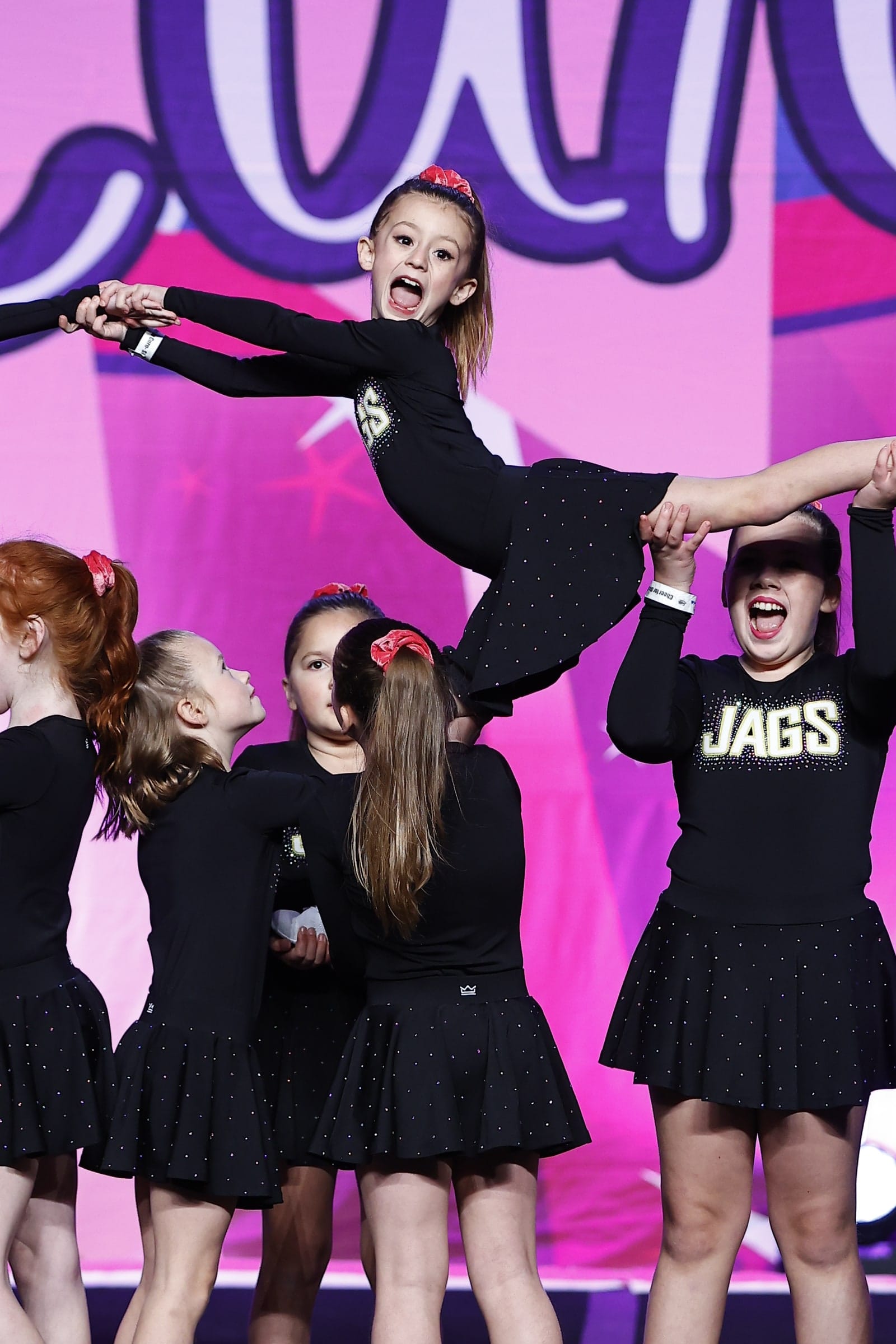 Novice Cheer athletes lifting a flyer during their routine