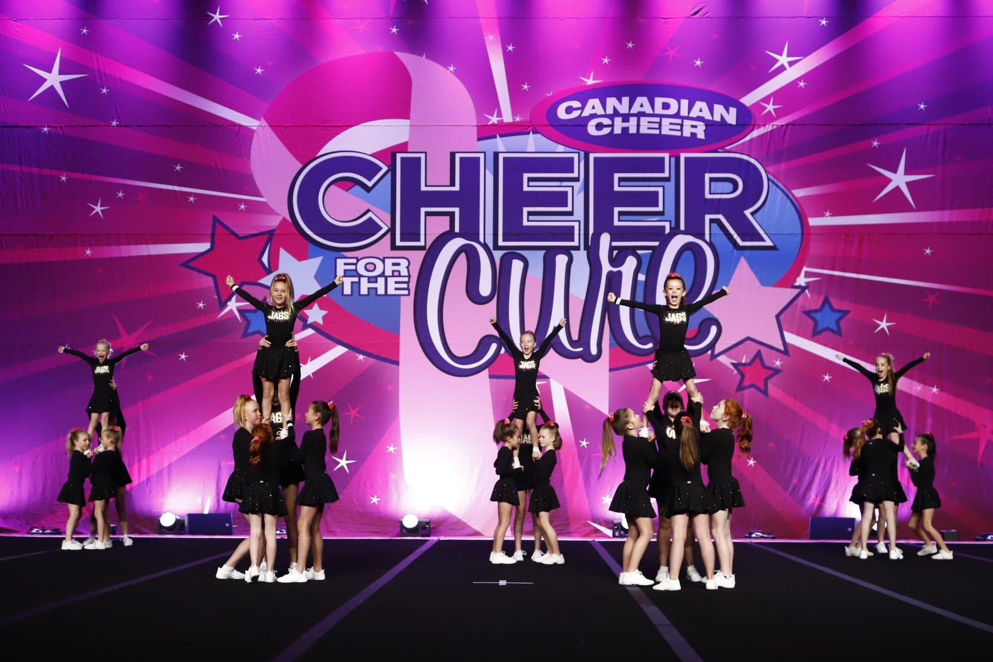 The Novice Cheer team in a pyramid on the Cheer for the Cure stage