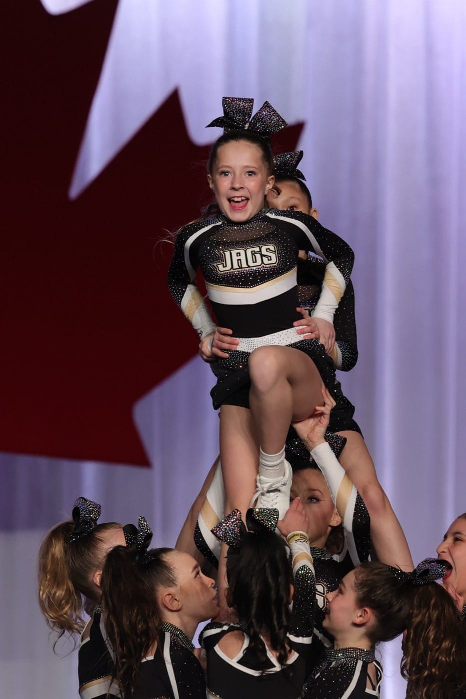 Prep Cheer athlete stunting in front of a Canadian flag backdrop